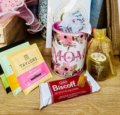 Mother's Day gift set with floral mom mug, tea assortment, honey jar, and Biscoff cookies for a cozy self care gift box.