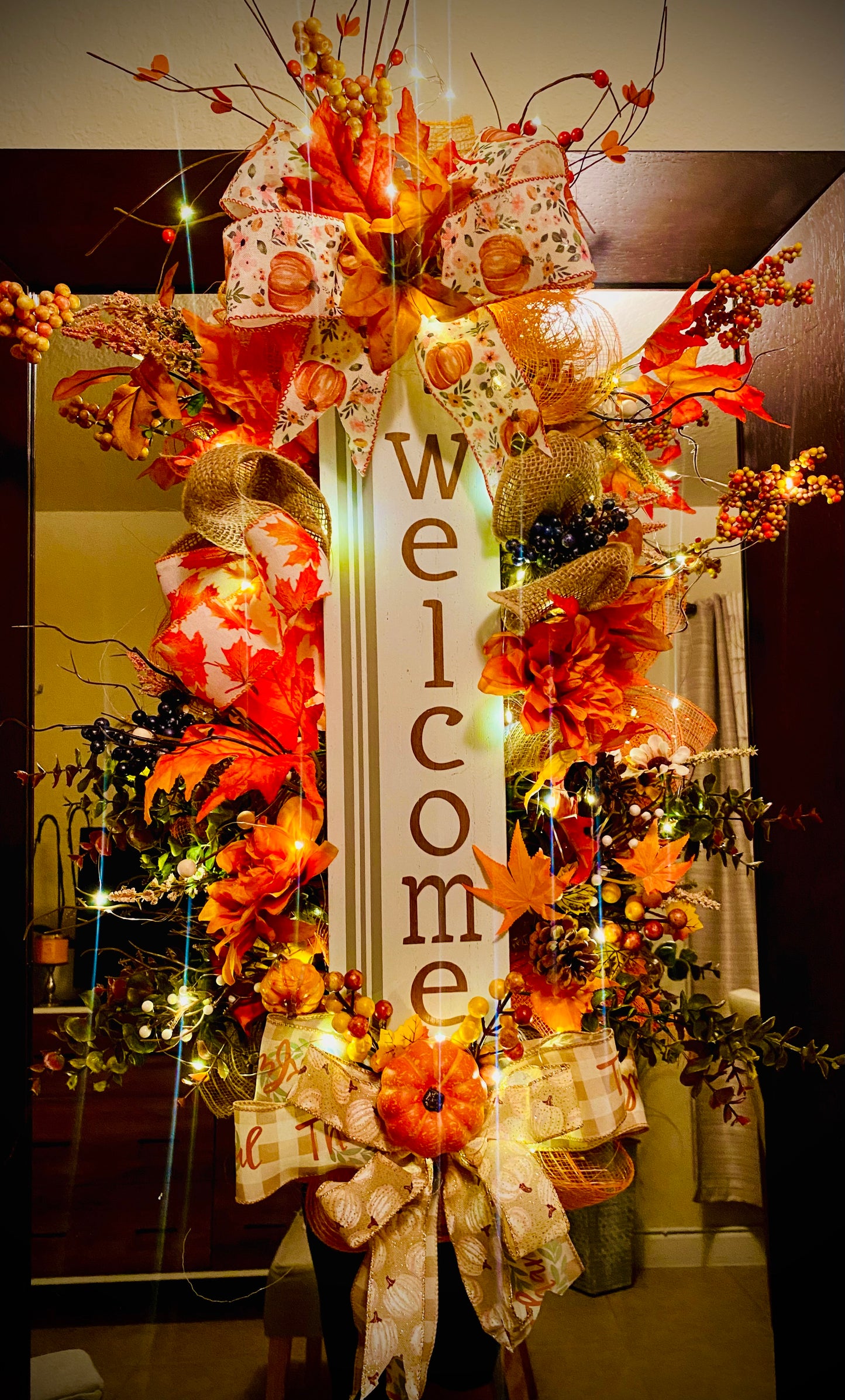 ): Lighted 24-inch fall welcome wreath glowing with warm LED fairy lights, orange pumpkins, dahlias, and a wood welcome sign