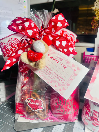 Boutique window gift bag with heart-patterned bow and plush bear keychain for Valentine's Day.
