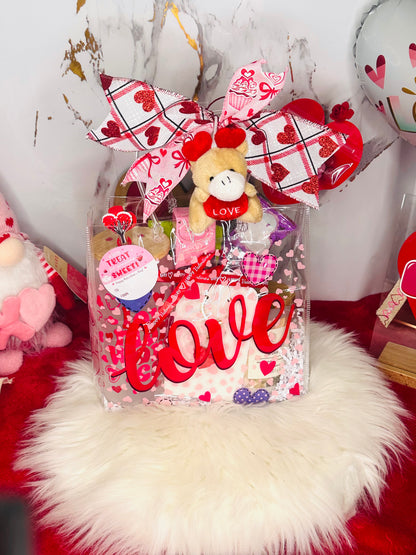 Valentine’s Day gift bundle featuring a 'Love More Worry Less' frosted glass tumbler with bamboo lid, a white Threshold candle, Lindt truffles, pistachios, snacks, and a pink gnome plush on a red background