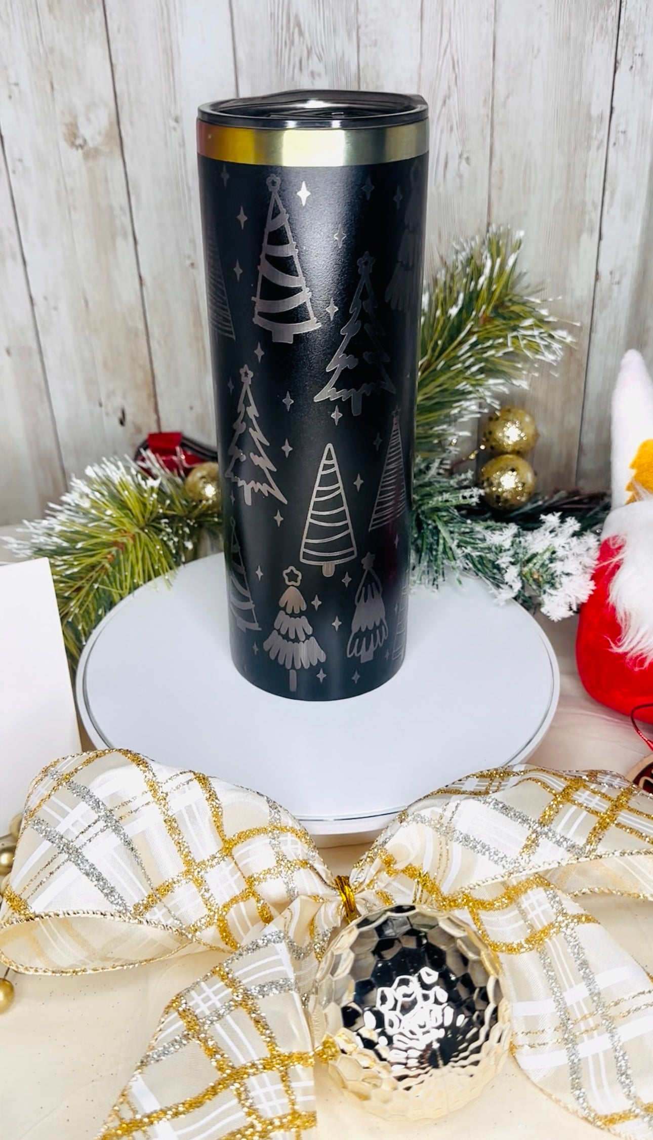 Black tumbler with Christmas tree design on a decorative surface .