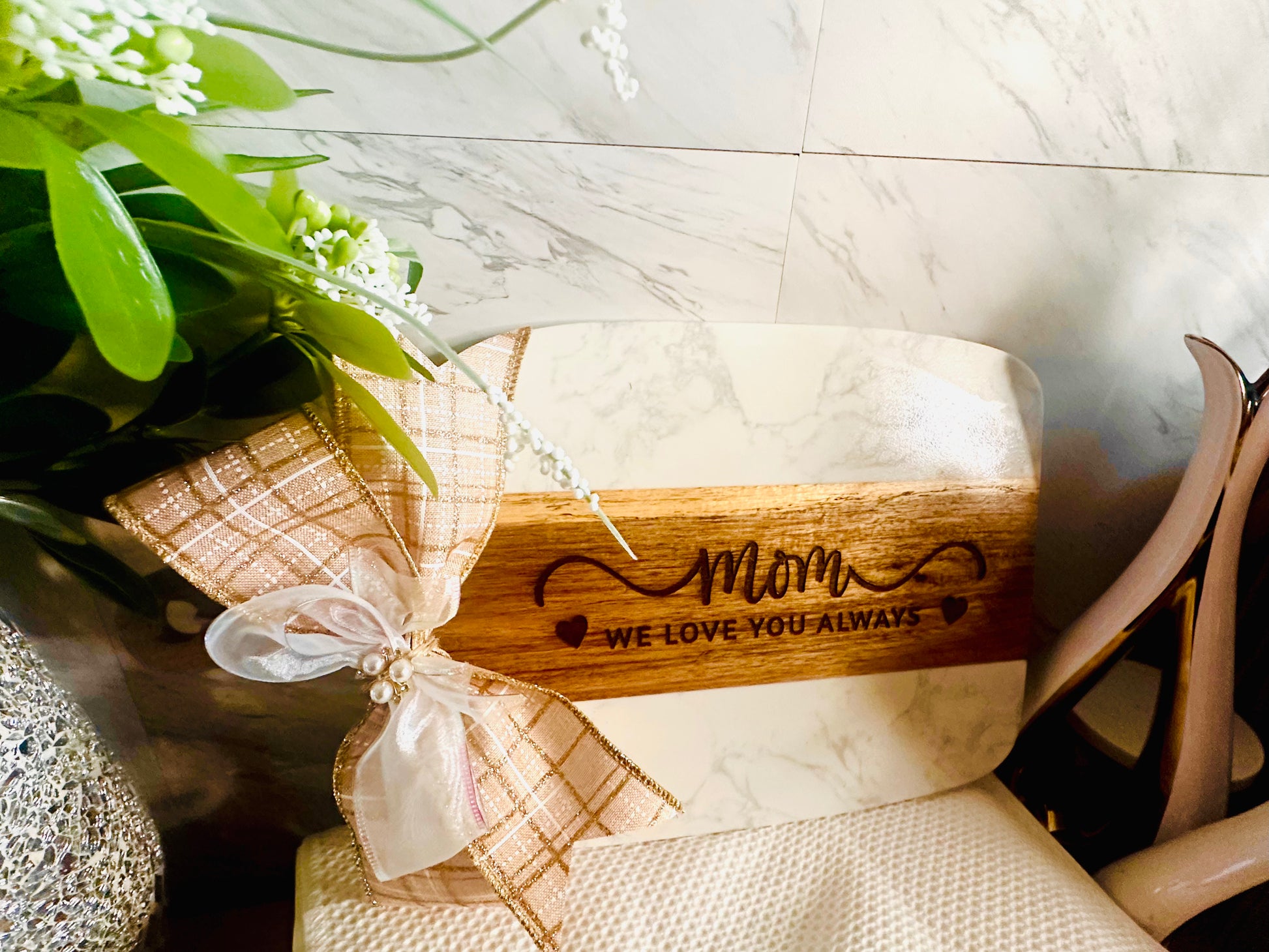 Wooden block with 'Mom, we love you always' engraving on a marble surface