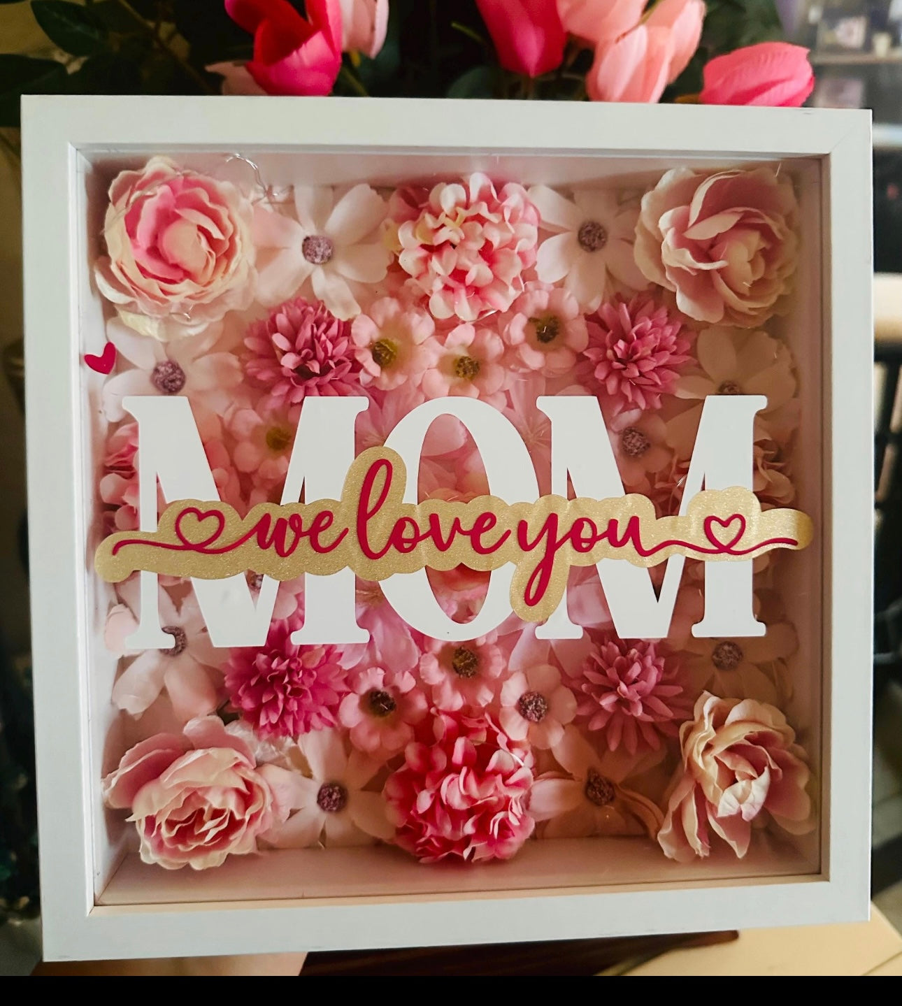 Personalized LED shadow box for mom with pink floral background, warm lights, and custom names under MOM text”