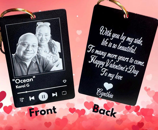 A personalized music plaque keychain in matte black with a custom couple's photo and song title, paired with a white insulated travel mug that says 'Coffee is my Valentine' and a box of chocolates