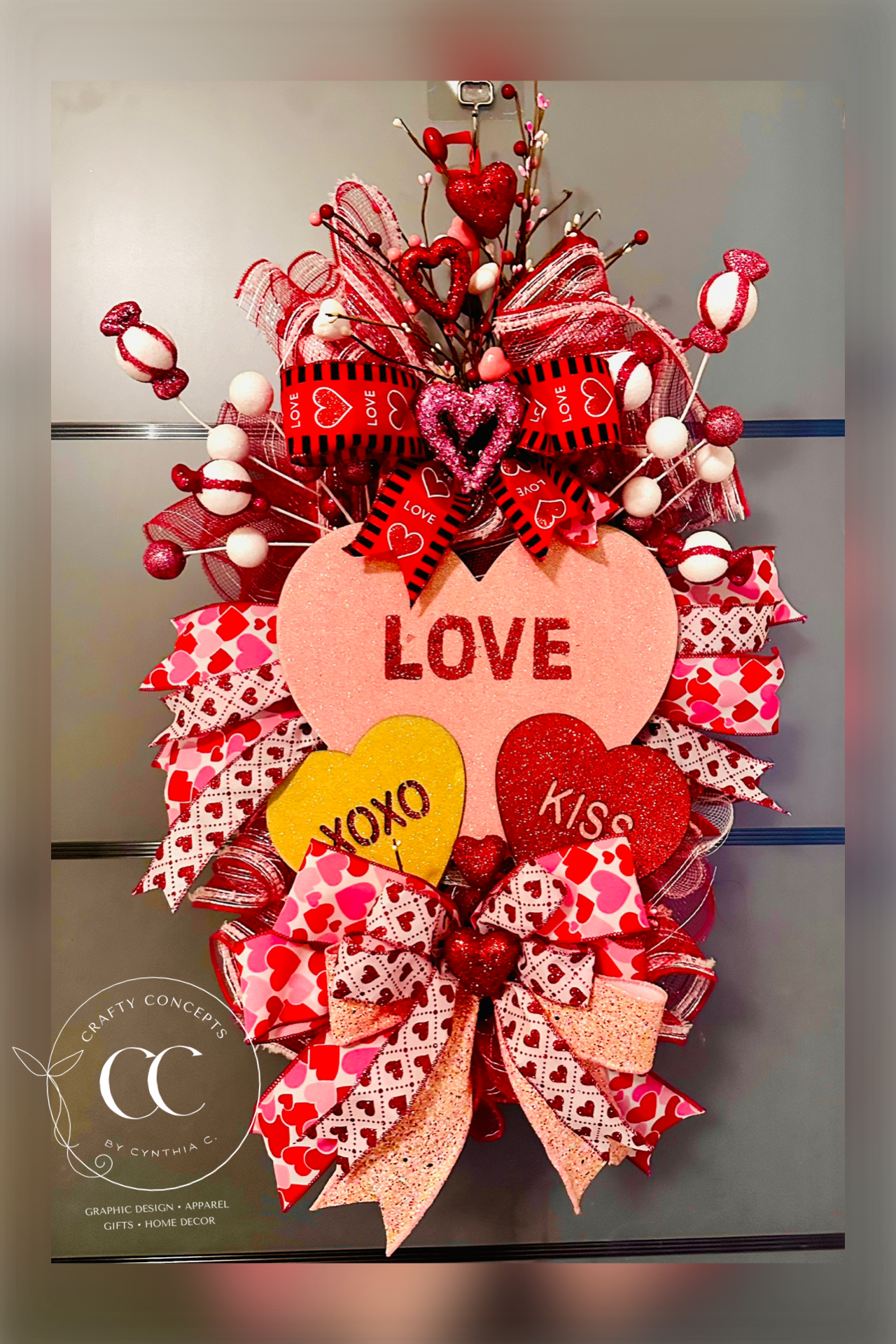 Add a touch of romance to your home with this stunning Valentine's Day teardrop door swag. Featuring "LOVE" and "XOXO" glitter hearts, premium layered ribbons and festive candy accents, this handmade wreath is the perfect front door statement piece or romantic gift. 