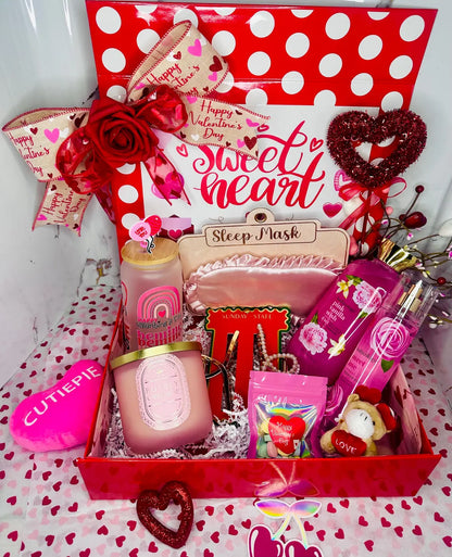 Close-up of the "Bubbly Champagne" aromatherapy candle in a frosted pink jar with a gold lid, nestled next to a "Be Mine Valentine" glass tumbler and pink satin sleep mask.