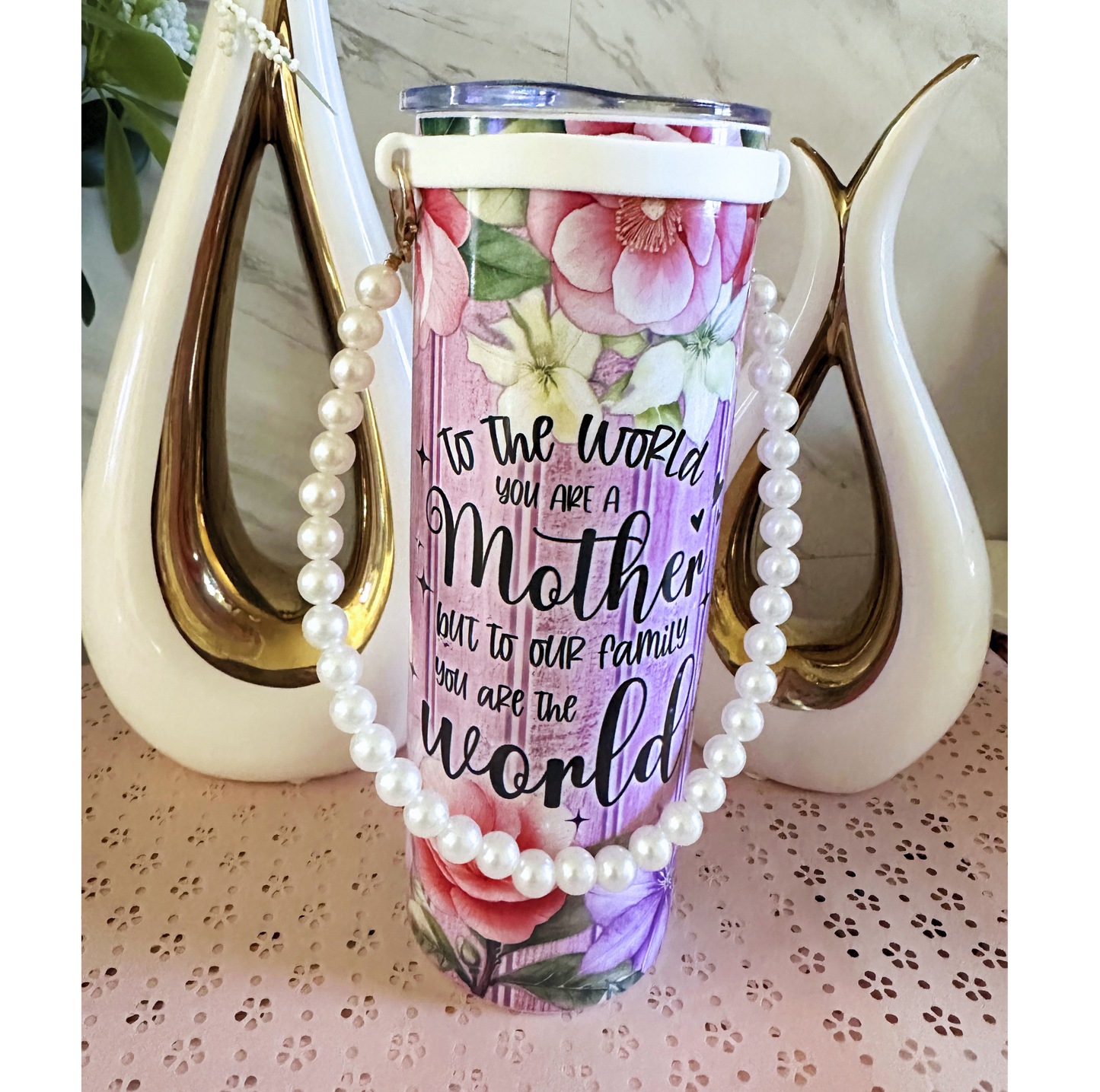 Tumbler with floral design and text, draped with pearls.