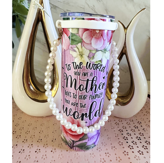 Tumbler with floral design and text, draped with pearls.